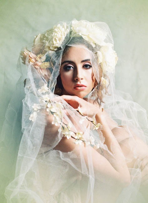 Female model wearing dramatic floral headpiece and veil.