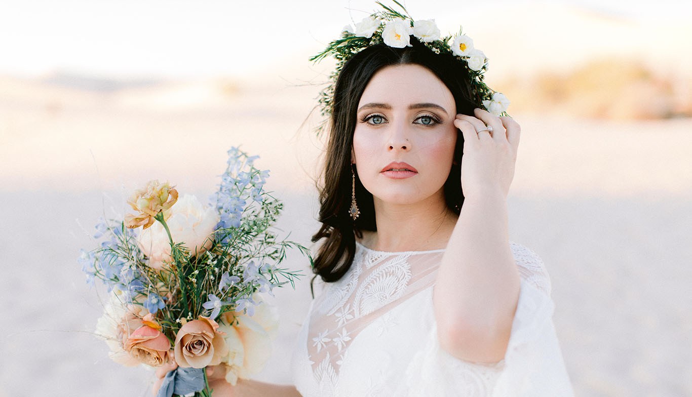 Attractive Brunette holding a bouquet of roses in a wedding dress while standing in front of a metal bannister indoors.